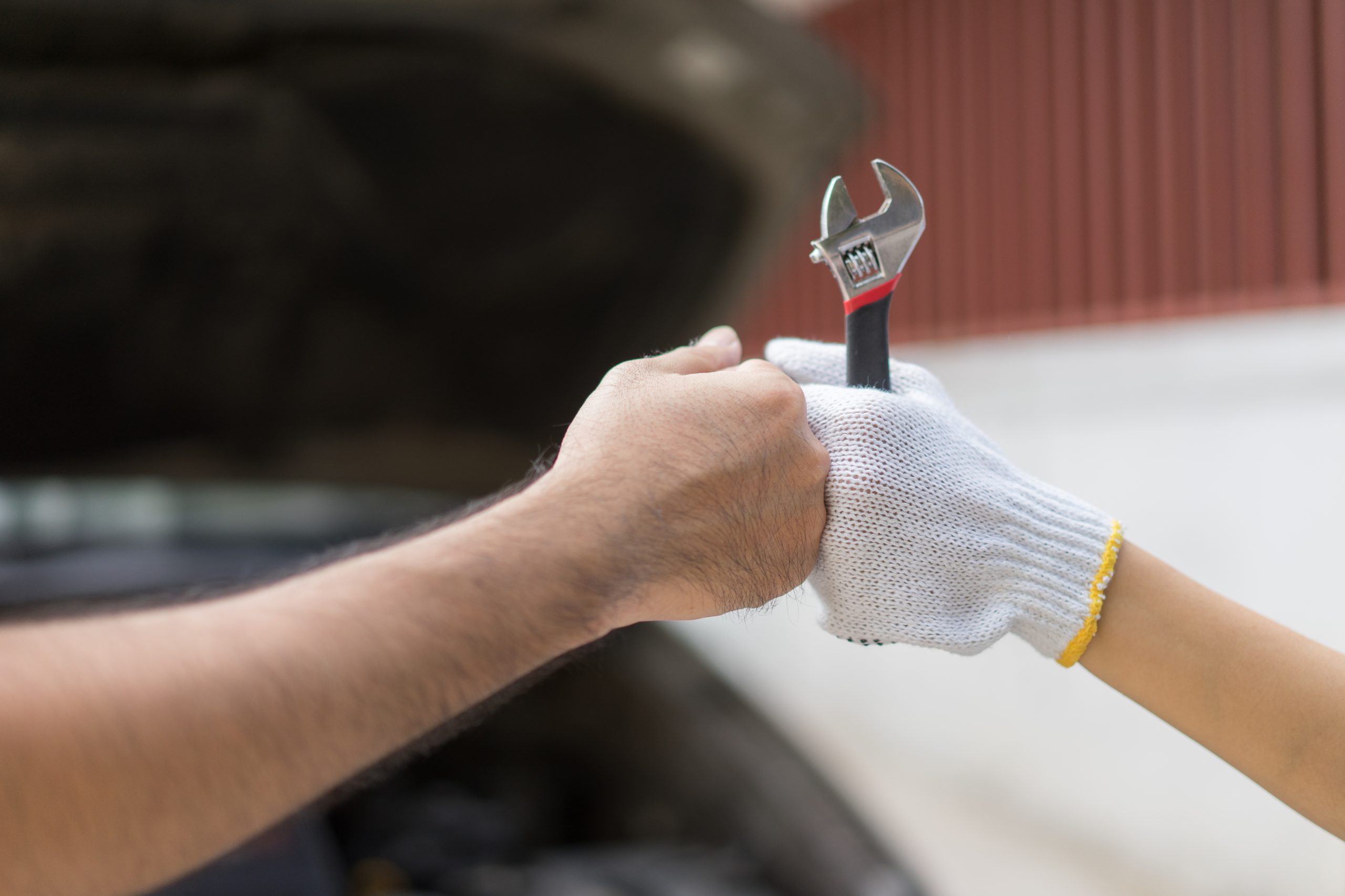 Mechanic hand checking and fixing a broken car in  garage.hand of mechanic with thumbs up and tool